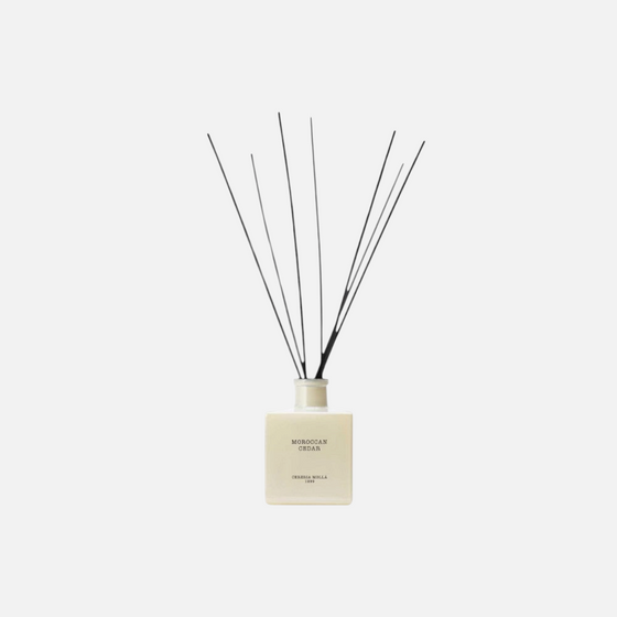 Citrine Home Moroccan Cedar reed diffuser in a square cream glass bottle with black reeds against a light background