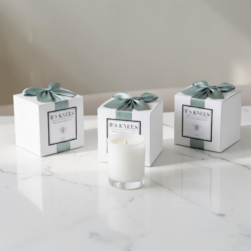 Citrine Home Aleja scented candle in a white glass jar with three matching gift boxes tied with sage green ribbons.