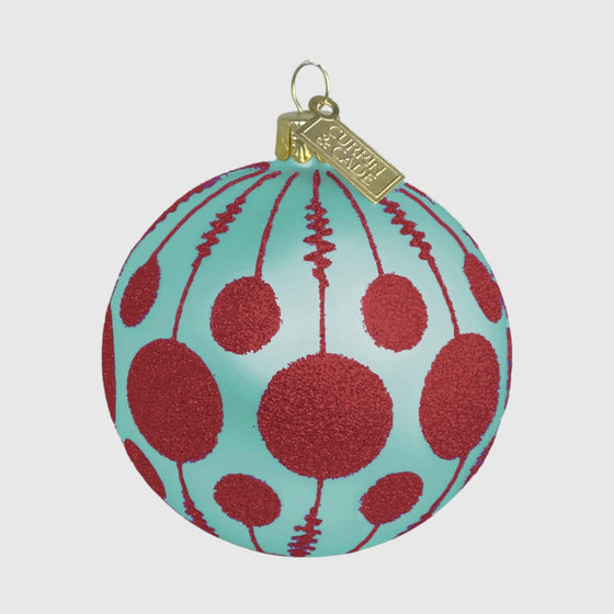 Citrine Home mouth-blown glass ornament in aqua with coral glitter lollipop patterns and a gold hanging tag.