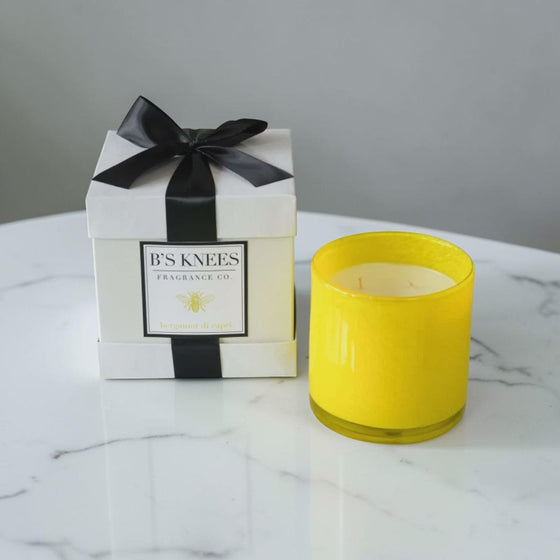 Citrine Home Bergamont di Capri 3-wick yellow glass candle next to a white gift box with a black ribbon