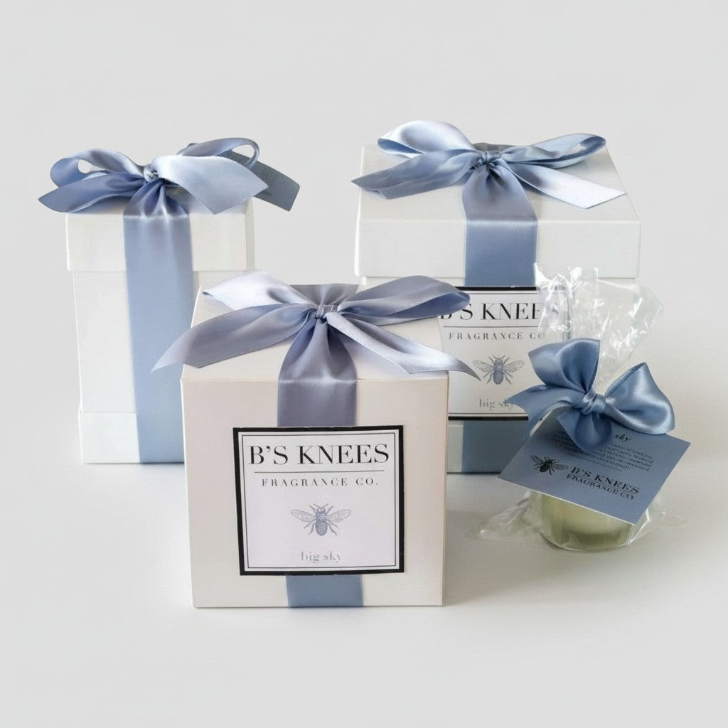 Citrine Home Big Sky fragrance gift set featuring white boxes with blue satin ribbons and a small candle