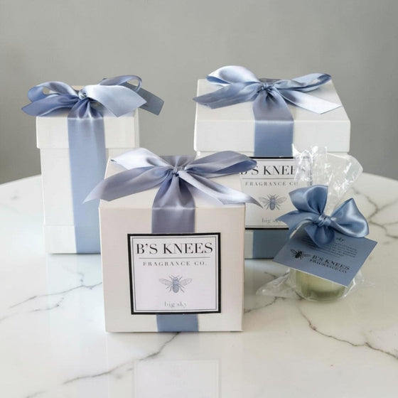 Citrine Home Big Sky fragrance gift set featuring white boxes with blue satin ribbons and a small wrapped candle