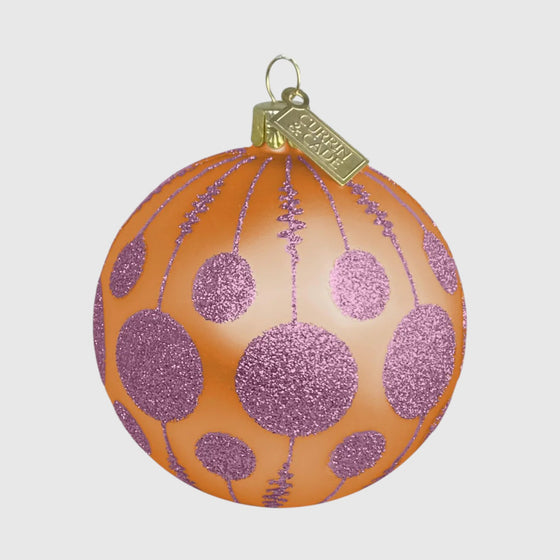 Citrine Home mouth-blown glass ornament in butterscotch orange with soft pink glitter polka dot and line patterns.