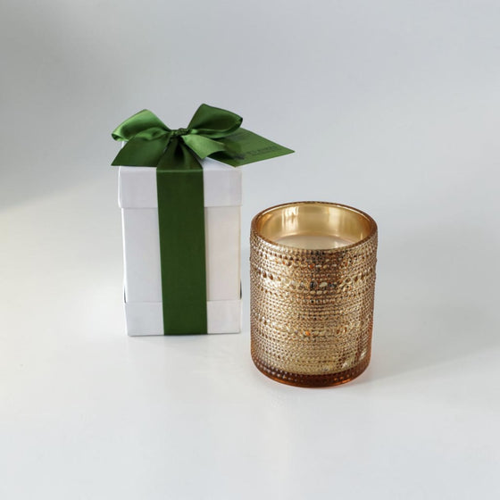 Citrine Home Fraser Fir & Balsam scented candle in a textured gold glass jar next to a white gift box with green ribbon