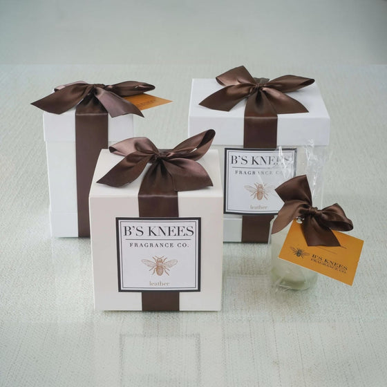 Citrine Home La Junta Leather 2-wick candle gift sets in white boxes with brown satin ribbons on a glass surface