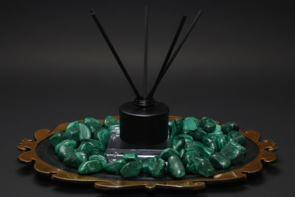 Citrine Home Malachite reed diffuser with black reeds, set on a decorative tray surrounded by green malachite stones.