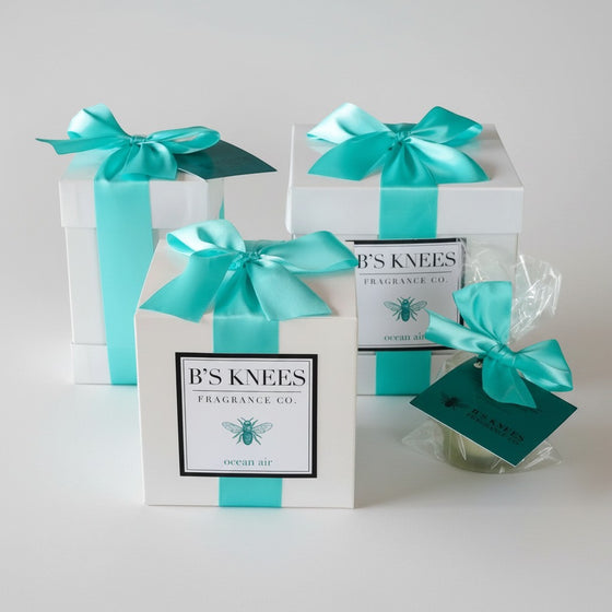 Citrine Home Ocean Air fragrance gift set featuring white boxes with teal satin ribbons and branded bee labels