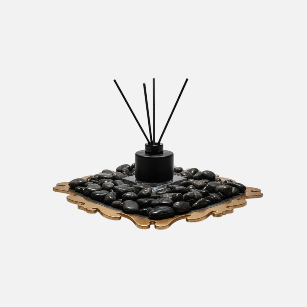 Citrine Home Onyx reed diffuser with black bottle and reeds set on a decorative gold tray with black river stones.