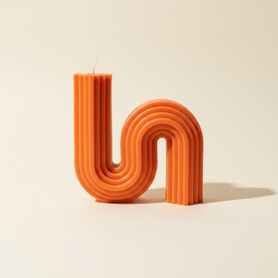 Citrine Home 70s style orange soy beeswax candle with a unique wavy, ribbed architectural design.