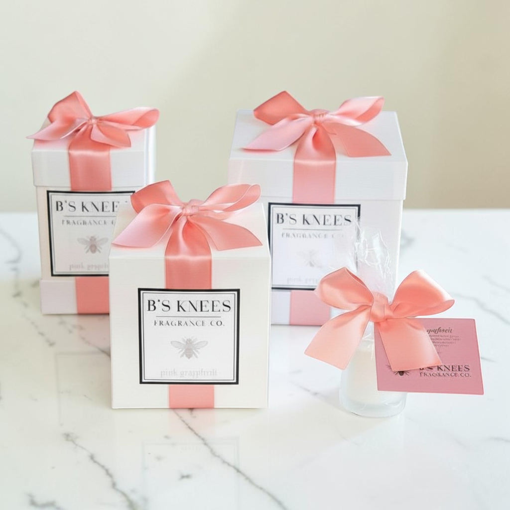 Citrine Home Pink Grapefruit scented candles in white gift boxes with pink satin ribbons on a marble surface