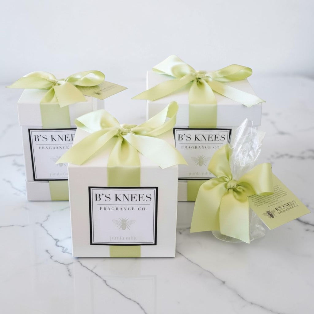 Citrine Home Punta Mita fragrance gift boxes with white packaging and light green satin ribbons on a marble surface.