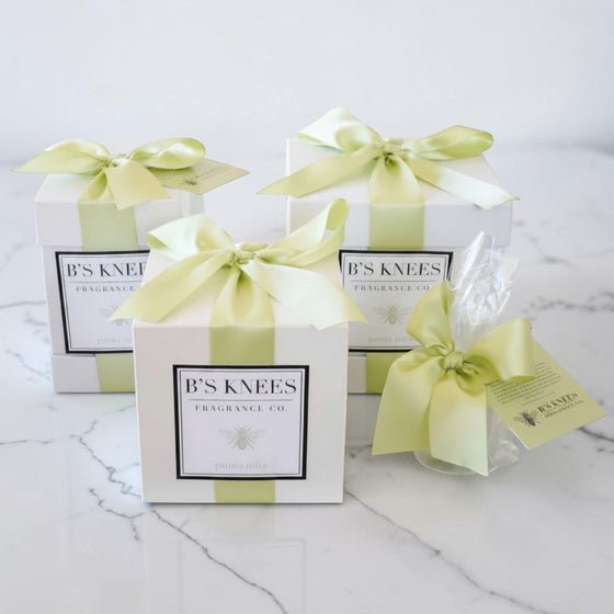 Citrine Home Punta Mita fragrance gift boxes with white packaging and light green satin ribbons on a marble surface.