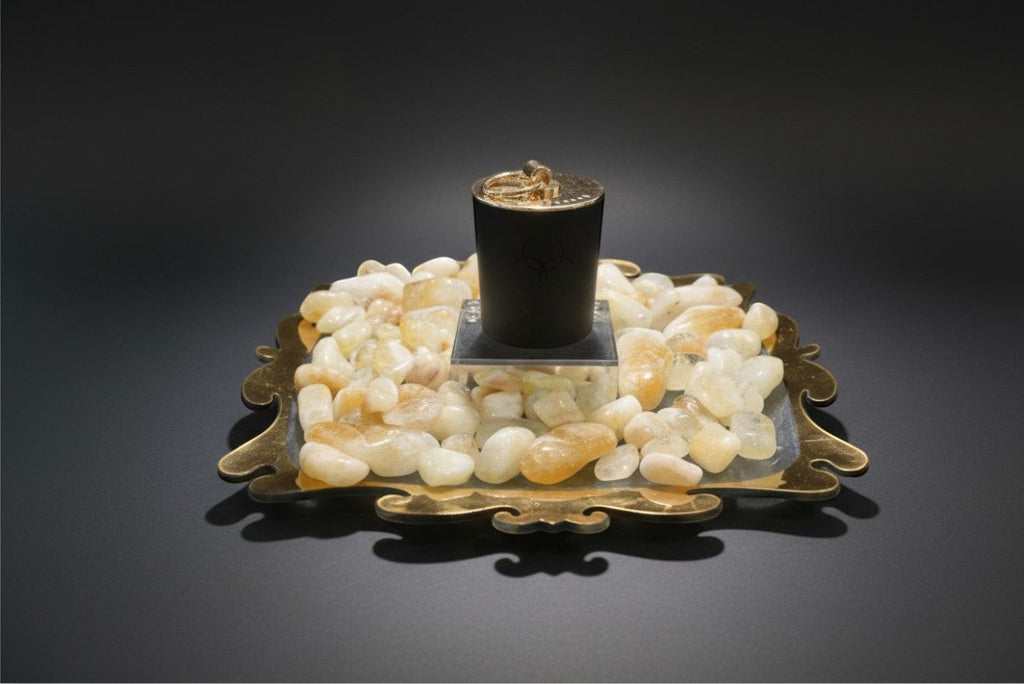 Citrine Home 8 oz Saffron Tobacco candle in a black jar resting on a decorative tray with polished citrine stones