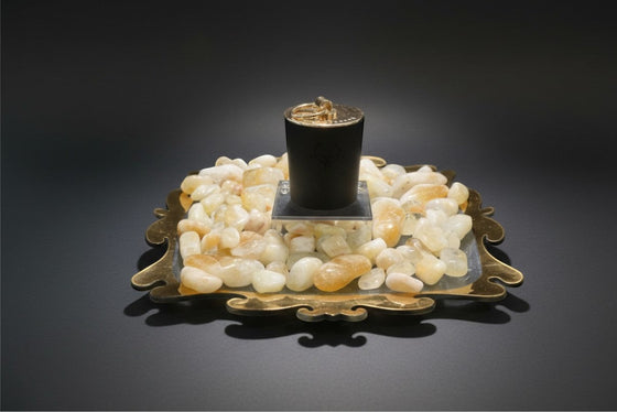 Citrine Home 8 oz Saffron Tobacco candle in a black jar resting on a decorative tray with polished citrine stones