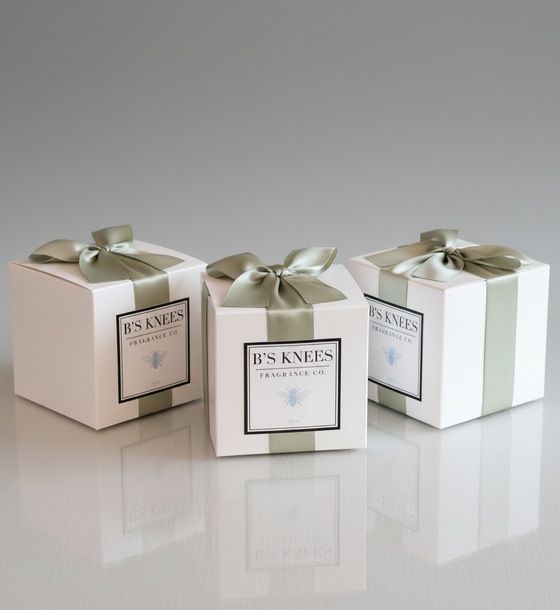 Three Citrine Home Spa fragrance gift boxes in white with sage green ribbons on a reflective surface.