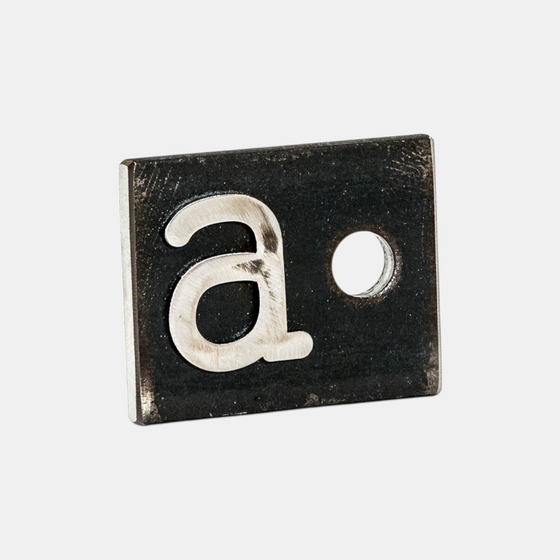 Citrine Home Original A Hole desk ornament crafted from dark scrap steel with a silver letter a and circular cutout