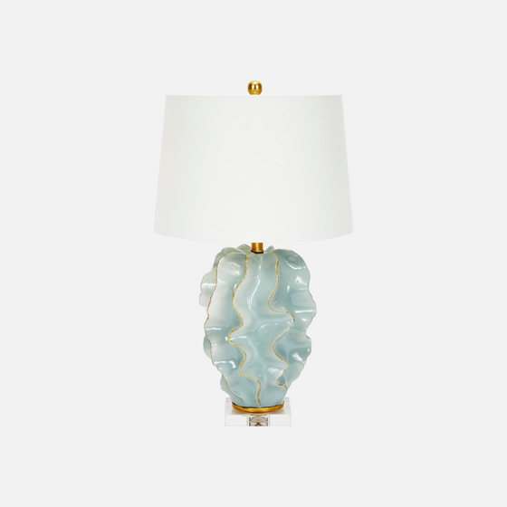 Citrine Home Hannah ceramic wave table lamp in blue with gold trim and a white linen drum shade on a clear base.