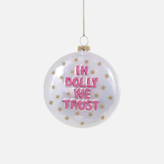 Citrine Home glass ornament featuring pink In Dolly We Trust text and gold star accents on a clear round bauble